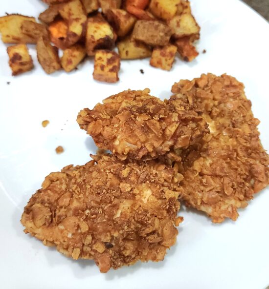 pretzel crunch chicken on white plate with potatoes as a side